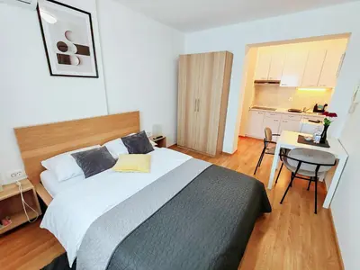 a bedroom with a bed and a table and a kitchen at Lucky center Ljubljana in Ljubljana