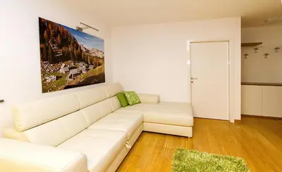 a living room with a white couch and a painting on the wall at Apartments Bohinjskih 7 in Bohinj