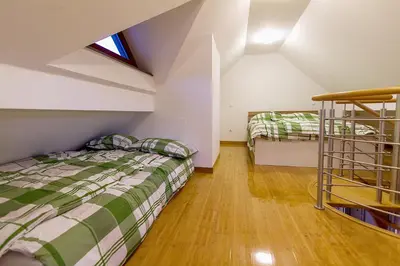 a attic bedroom with two beds and a ladder at Apartments Bohinjskih 7 in Bohinj