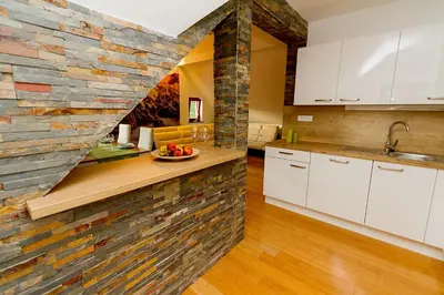 a kitchen with a brick wall and white cabinets at Apartments Bohinjskih 7 in Bohinj