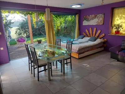 a dining room with a glass table and chairs and a bed at Guest House Bitter in Braslovče