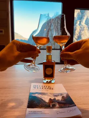 two people holding wine glasses and a bottle of whiskey at Radovna Chalet with Panoramic View in Mojstrana