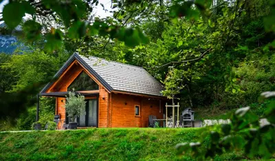 a small wooden house in the middle of a field at Radovna Chalet with Panoramic View in Mojstrana