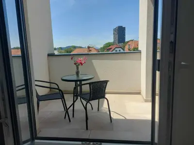 a table and chairs on a balcony with a vase of flowers at PALAR Apartment in Ljubljana