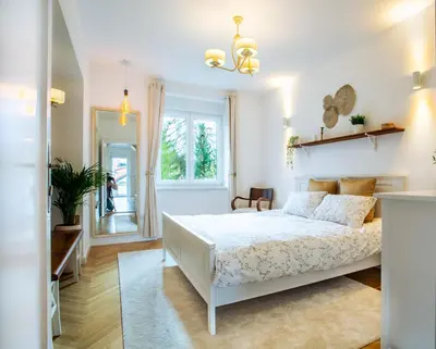 a white bedroom with a bed and a window at Pipa’s Place - Stylish garden prime location apt in Ljubljana