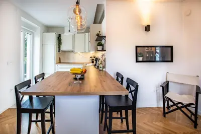 a kitchen and dining room with a wooden table and chairs at Pipa’s Place - Stylish garden prime location apt in Ljubljana