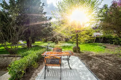 a table and chairs in a garden with the sun shining at Pipa’s Place - Stylish garden prime location apt in Ljubljana