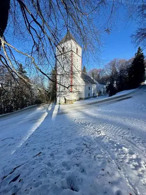 a snow covered road with a building with a tower at SkiCity Apartment Pohorje Bellevue in Pohorje