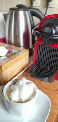 a cup of coffee on a table next to a tea kettle at Idyllic Retreat Next to an Elven Forest in Gozd Martuljek