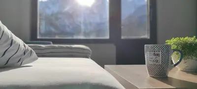 a coffee cup sitting on a table next to a bed at Idyllic Retreat Next to an Elven Forest in Gozd Martuljek