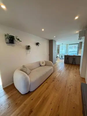 a white couch in a living room with a wooden floor at Penthouse Apartment - Garden Residence in Ljubljana