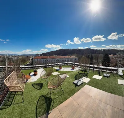 a patio with chairs and tables on the grass at Penthouse Apartment - Garden Residence in Ljubljana