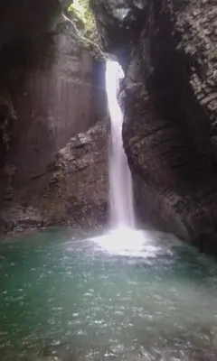 a waterfall in a cave with a pool of water at Apartment Kolman in Tolmin