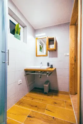 a bathroom with a sink and a wooden floor at Apartment House VINARIA in Zgornja Ložnica