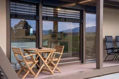 a wooden table and chairs on a porch with windows at Fortun Estate - apartmaji ob reki Kolpi in Metlika