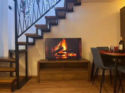 a tv sitting on a stand in a living room with a fire at Apartman LA CASA 77B in Ljubljana
