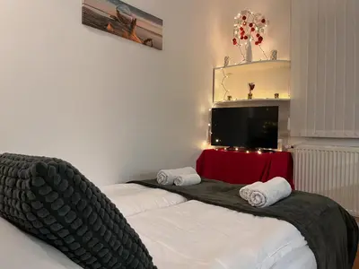 two beds in a room with a tv on the wall at Apartman LA CASA 77A in Ljubljana
