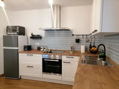a kitchen with white cabinets and a stainless steel refrigerator at Lukova hiša- Luka's house in Vipava