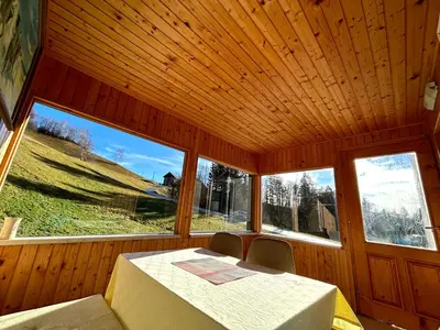 a dining room with a table and two windows at Apartma Bine in Cerkno
