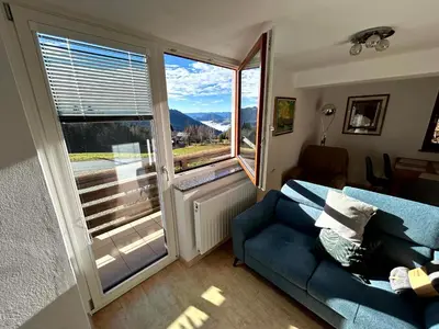 a living room with a blue couch and a large window at Apartma Bine in Cerkno