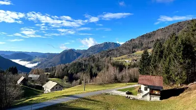 a house on the side of a hill with a road at Apartma Bine in Cerkno