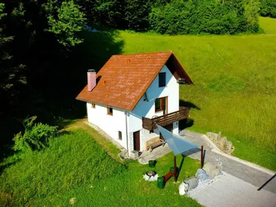a small white house with a red roof on a green field at Apartma Bine in Cerkno