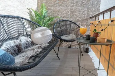 a patio with a chair and a table with a pillow at Old Town's Legend: City center condo with balcony in Maribor