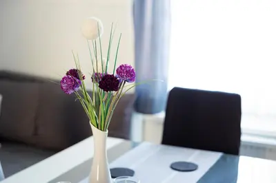 a white vase with purple flowers on a table at Apartma Ella in Lovrenc na Pohorju