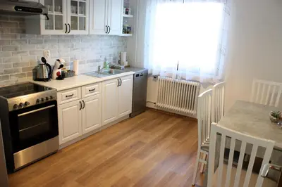 a kitchen with white cabinets and a wooden floor at Apartment Jona, Bled in Bled