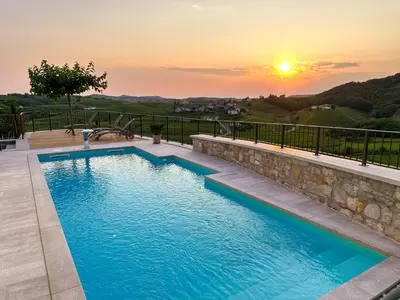 a swimming pool with a sunset in the background at Ca' S Lorenz - A Luxury 100m2 Apartment in a Chic Vineyard Villa in Dobrovo