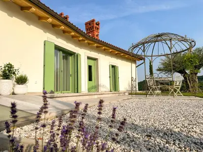 a house with a courtyard with a chair and a garden at Ca' S Lorenz - A Luxury 100m2 Apartment in a Chic Vineyard Villa in Dobrovo