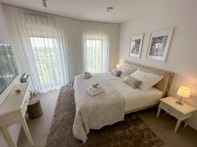 a bedroom with a large bed with two tables and two windows at Ca' S Lorenz - A Luxury 100m2 Apartment in a Chic Vineyard Villa in Dobrovo