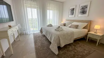 a white bedroom with a large bed and two windows at Ca' S Lorenz - A Luxury 100m2 Apartment in a Chic Vineyard Villa in Dobrovo