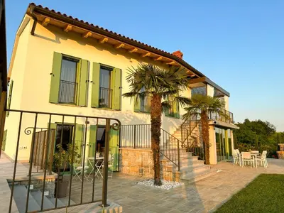 a house with two palm trees in front of it at Ca' S Lorenz - A Luxury 100m2 Apartment in a Chic Vineyard Villa in Dobrovo