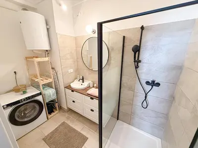 a bathroom with a shower and a sink and a washing machine at The North Apartment in Ljubljana