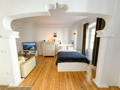 a white bedroom with a bed and a dresser at The North Apartment in Ljubljana