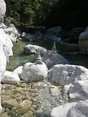a stream with rocks and a river with two towers at Apartment Šavli in Kobarid