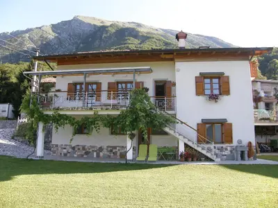 a large white house with a mountain in the background at Apartment Šavli in Kobarid