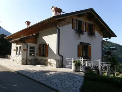 a small white house with wooden shuttered windows at Apartment Šavli in Kobarid