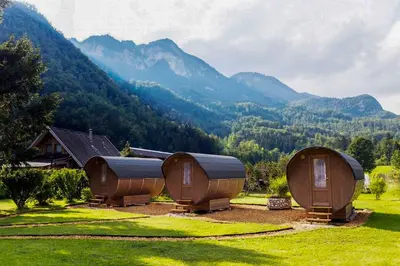 a group of cottages in a field with mountains in the background at 4 Elements Glamping & Apartments in Bled