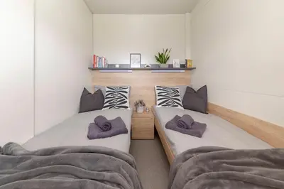 two twin beds in a room with white walls at Apartma LeMa in Velike Lašče
