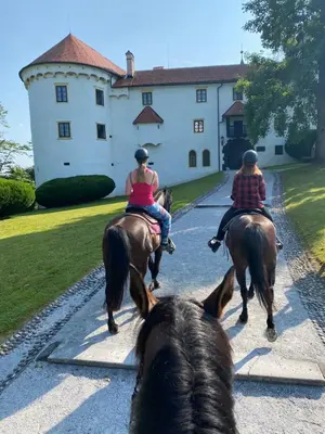 three people riding horses in front of a castle at Gracarjeva domačija in Mišji Dol