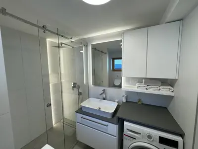 a bathroom with a shower and a sink and a washing machine at Gloria Holiday - Kranjska Gora Apartments in Kranjska Gora