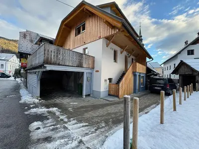 a house with a wooden roof in the snow at Gloria Holiday - Kranjska Gora Apartments in Kranjska Gora