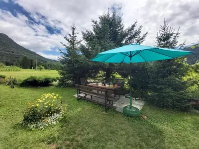 a picnic table with an umbrella next to a bench at Apartma Brešan in Kobarid