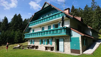 a woman standing in front of a house at Apartma Jurček Rogla in Rakovec