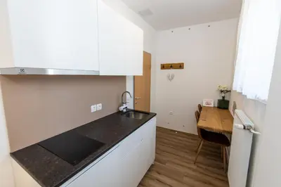 a kitchen with white cabinets and a wooden table at Apartment Muznik in Bled