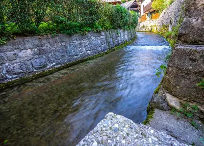 a small stream of water next to a stone wall at Apartment Muznik in Bled