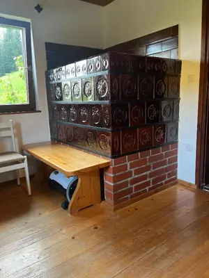 a room with a brick fireplace with a wooden table at Hiška pri Vrjaku in Bohinjska Bistrica