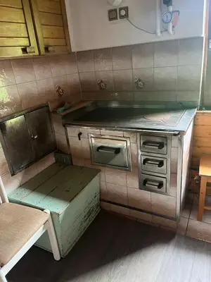 an old kitchen with a stove and a bench at Hiška pri Vrjaku in Bohinjska Bistrica